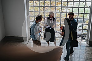 Group of students discussing with professor in university corridor