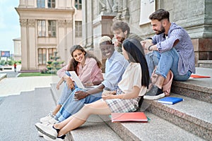 group of students discussing something on the steps of the university .