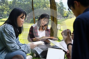 Group of students doing group project together while sitting in university campus. Education and youth lifestyle concept