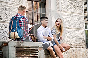 Group of students in front of university studying, having fun.