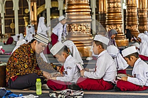 Group of students learning to read Quran with teachers in a mosque