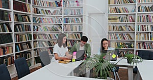 Group of students preparing for exam in university library. Happy diverse students talking, learning, studying together