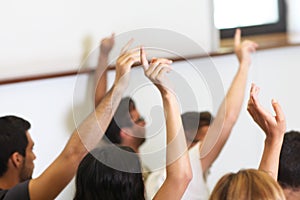 Group of students put hand up in class room