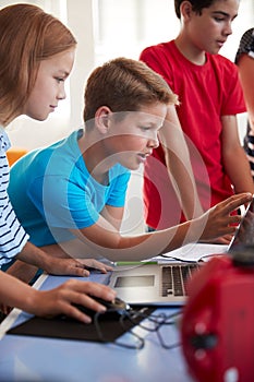 Group Of Students In After School Computer Coding Class Learning To Program Robot Vehicle