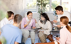 Group of students sitting in circle studying together in study hall of university