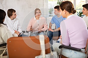 Group of students sitting in circle studying together in study hall of university