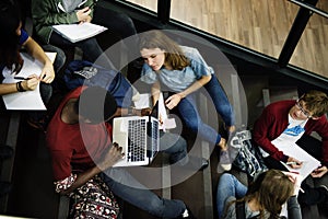Group of students sitting on staircase using laptop