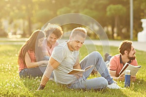 A group of students studying books sitting in a city park.