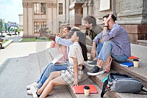group of students talking on a video link sitting on the steps.