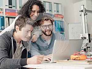 Group of students using a 3D printer and a laptop