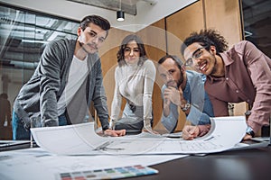 group of successful architects discussing plans and looking at camera