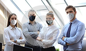 Group of successful business people in preventive masks during epidemy on the background of the office.