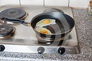 Group of sunny side up eggs with yellow yolks cooking in silver skillet