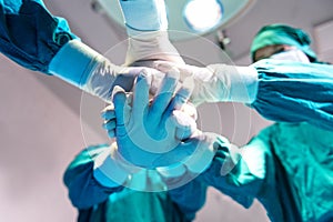 Group Surgeon doctor joining hands before Patient surgery in hospital operating room.