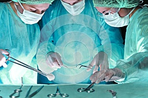 Group of surgeons in masks performing operation. Scene of operation room colored in green. Medicine, surgery and