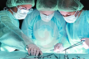 Group of surgeons in masks performing operation. Scene of operation room colored in green. Medicine, surgery and