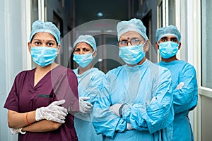 group of surgeons and practitioners confident standing with arms crossed by looking camera at hospital corridor -