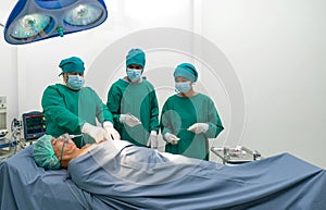Group of surgeons, steeped in concentration, performing complex surgery in operating room. Sterile surgical instruments pepper the