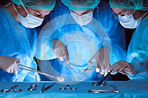 Group of surgeons wearing safety masks performing operation. Close-up of surgery tools. Medicine concept