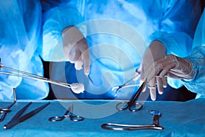 Group of surgeons wearing safety masks performing operation. Close-up of surgery tools. Medicine concept