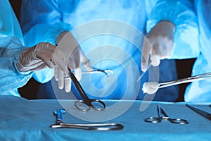 Group of surgeons wearing safety masks performing operation. Close-up of surgery tools. Medicine concept