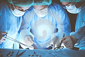 Group of surgeons wearing safety masks performing operation. Close-up of surgery tools. Medicine concept