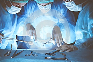 Group of surgeons wearing safety masks performing operation. Close-up of surgery tools. Medicine concept