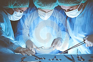 Group of surgeons wearing safety masks performing operation. Close-up of surgery tools. Medicine concept