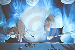 Group of surgeons wearing safety masks performing operation. Close-up of surgery tools. Medicine concept