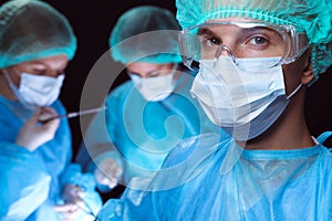 Group of surgeons wearing safety masks performing operation. Medicine concept