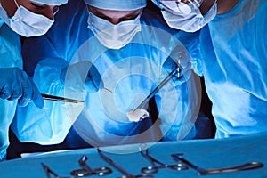 Group of surgeons wearing safety masks performing operation. Medicine concept