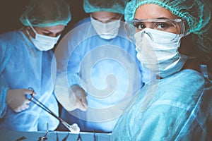 Group of surgeons wearing safety masks performing operation. Medicine concept