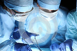 Group of surgeons at work operating in surgical theatre