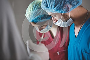 Group of surgeons at work operating in surgical theatre. Resuscitation medicine team wearing protective masks holding