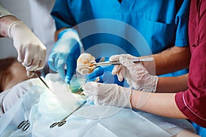 Group of surgeons at work operating in surgical theatre. Resuscitation medicine team wearing protective masks holding