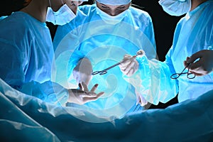 Group of surgeons at work in operating theater toned in blue