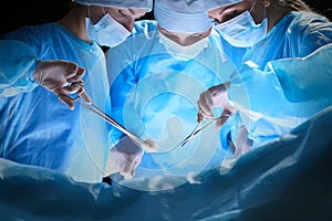 Group of surgeons at work in operating theater toned in blue