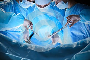 Group of surgeons at work in operating theater toned in blue