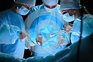 Group of surgeons at work in operating theater toned in blue