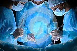 Group of surgeons at work in operating theater toned in blue