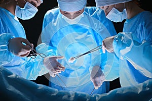 Group of surgeons at work in operating theater toned in blue