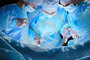 Group of surgeons at work in operating theater toned in blue