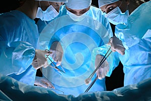 Group of surgeons at work in operating theater toned in blue