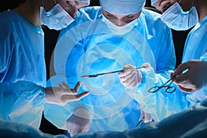 Group of surgeons at work in operating theater toned in blue