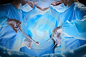 Group of surgeons at work in operating theater toned in blue