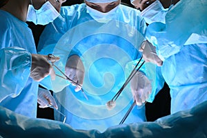 Group of surgeons at work in operating theater toned in blue