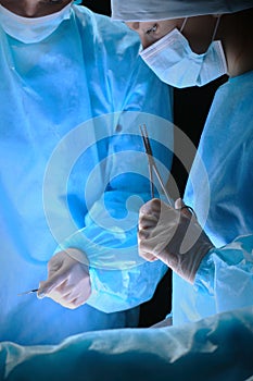 Group of surgeons at work in operating theater toned in blue