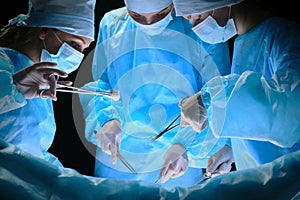 Group of surgeons at work in operating theater toned in blue