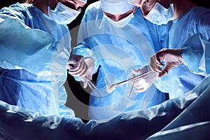 Group of surgeons at work in operating theater toned in blue