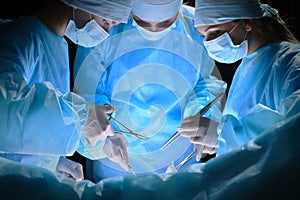 Group of surgeons at work in operating theater toned in blue